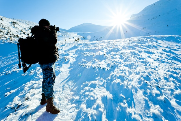 Jonge mensenfotograaf in de winterkleding die en foto in zonlicht bevinden zich maken