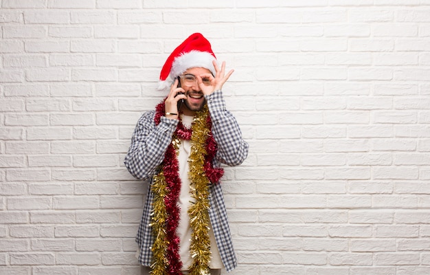 Jonge mensenzitting met giften die Kerstmis zeker doend ok gebaar op oog vieren