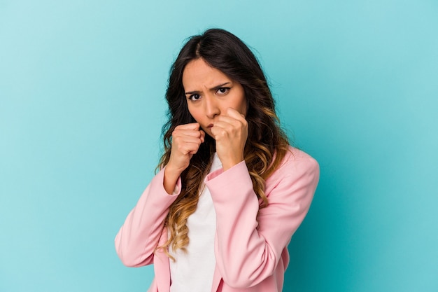 Jonge Mexicaanse vrouw die op blauwe muur wordt geïsoleerd die een klap, woede werpt, vecht wegens een argument, boksen.