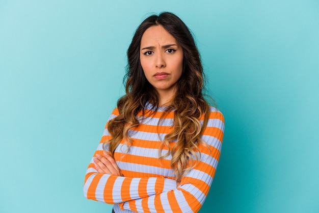 Jonge Mexicaanse vrouw die op blauwe muur wordt geïsoleerd die verveeld, vermoeid is en een ontspannende dag nodig heeft.