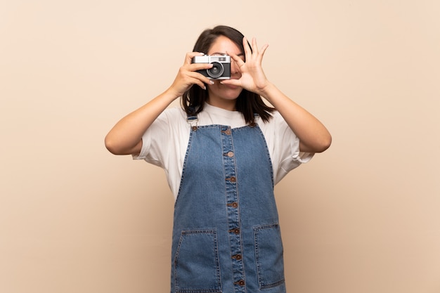 Jonge Mexicaanse vrouw die over geïsoleerde muur een camera houdt