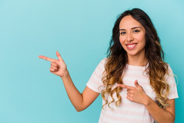 Jonge Mexicaanse vrouw geïsoleerd op blauwe muur geschokt wijzend met wijsvingers naar een kopie ruimte.