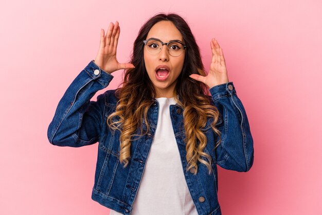 Jonge mexicaanse vrouw geïsoleerd op roze achtergrond die een overwinning of succes viert, hij is verrast en geschokt.