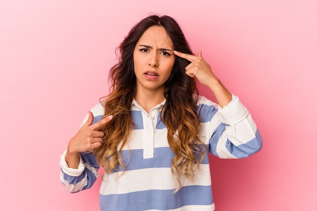 Foto jonge mexicaanse vrouw geïsoleerd op roze achtergrond met een gebaar van teleurstelling met wijsvinger.