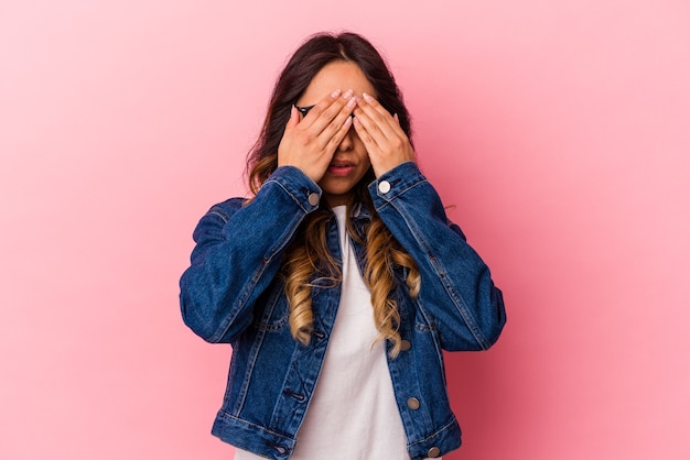 Jonge Mexicaanse vrouw geïsoleerd op roze muur bang voor ogen met handen.