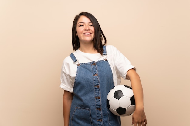 Jonge Mexicaanse vrouw over geïsoleerd houdend een voetbalbal