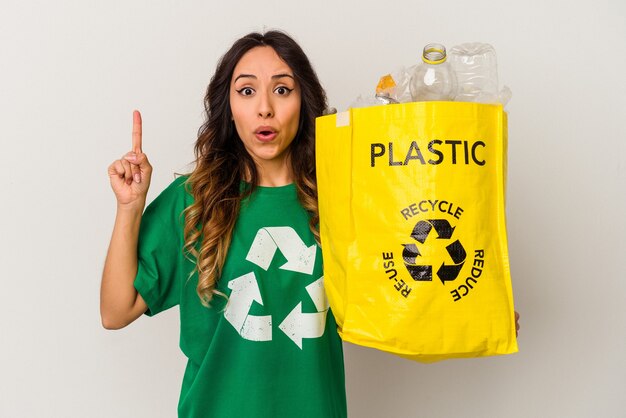 Jonge Mexicaanse vrouw recycling plastic geïsoleerd op een witte achtergrond met een geweldig idee, concept van creativiteit.