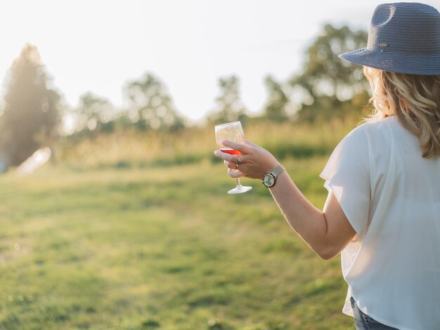 Jonge millennial vrouw met een glas wijn in een appelboomgaard