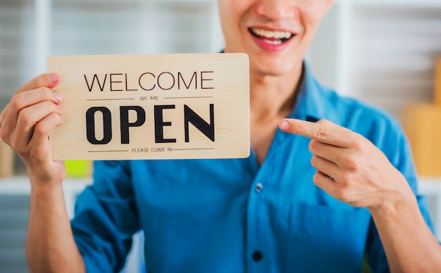 Jonge mkb-bedrijfsmens die open teken houden bij pakhuis.