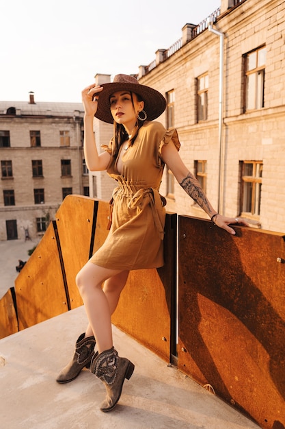 Jonge mode vrouw gekleed in een zomerjurk met een rieten brede hoed wandelingen en poses in de oude stad.