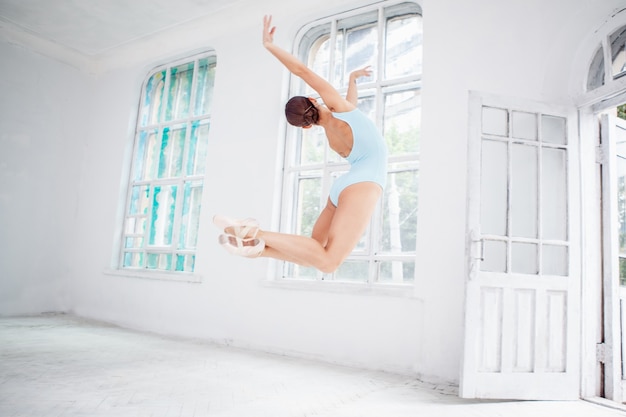 Jonge moderne balletdanser die op witte achtergrond springt