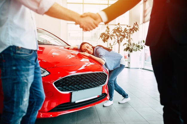 Foto jonge moderne gelukkige paar kopen van een nieuwe auto in stadsdealer en praten met verkoper
