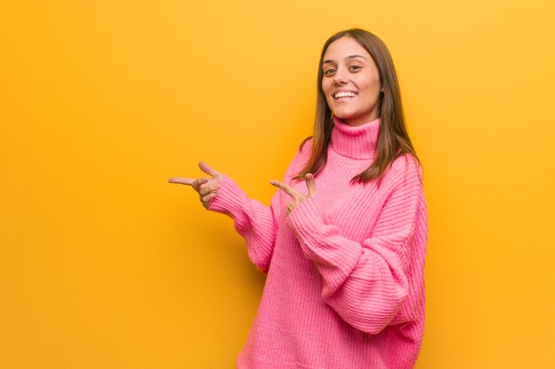 Jonge moderne vrouw die aan de kant met vinger richt