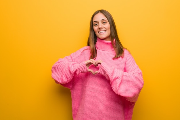 Jonge moderne vrouw die een hartvorm met handen doet