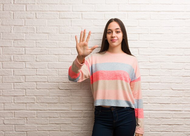 Jonge moderne vrouw die nummer vijf toont