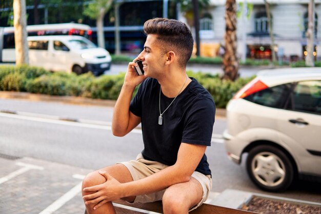 Jonge modieuze knappe man op straat van de moderne stad praten op een mobiele telefoon. Communicatie concept