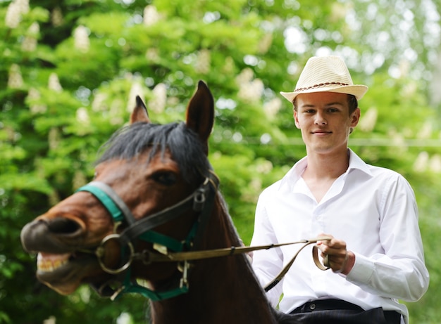 Jonge modieuze mens die berijdend een paard op platteland neemt