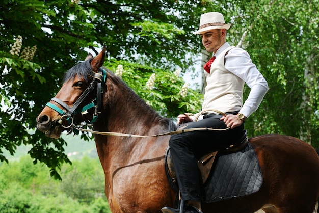 Jonge modieuze mens die berijdend een paard op platteland neemt