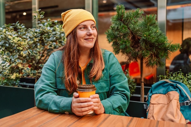 Jonge modieuze vrouw het drinken koffie om in een stadsstraat te gaan