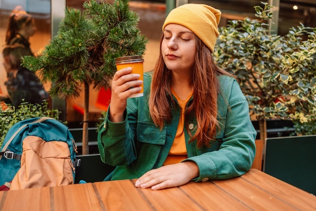 Jonge modieuze vrouw het drinken koffie om in een stadsstraat te gaan