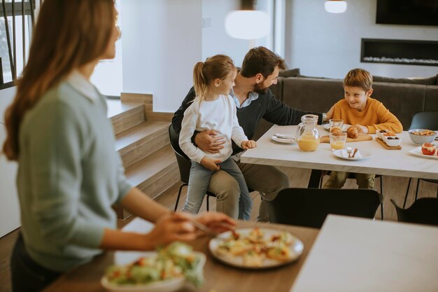 Jonge moeder bereidt ontbijt voor haar gezin in de moderne keuken