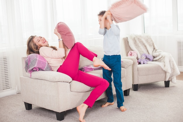 Jonge moeder die actieve spelen met haar zoon speelt. Vrolijke familie binnenshuis plezier.