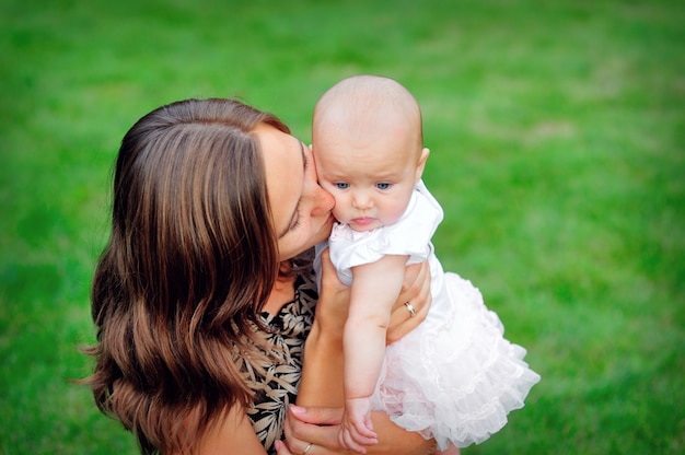 Jonge moeder die haar babydochter kust