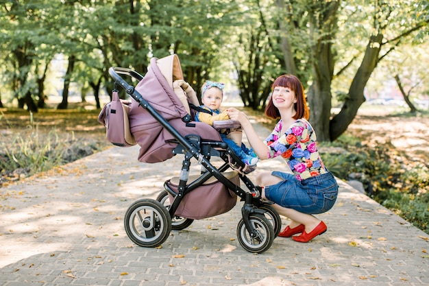 Jonge moeder die haar kind in een kinderwagen bekijkt