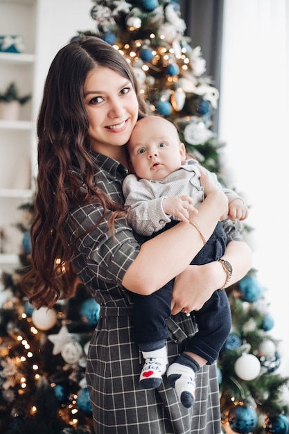 Jonge moeder die haar kleine kind met Kerstmis vasthoudt