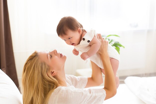 Jonge moeder die haar pasgeboren kind vasthoudt. Gelukkig moeder zogende baby. Vrouw en pasgeboren meisje samen in een witte slaapkamer thuis. Moeder borstvoeding baby. Gezinslevensstijl