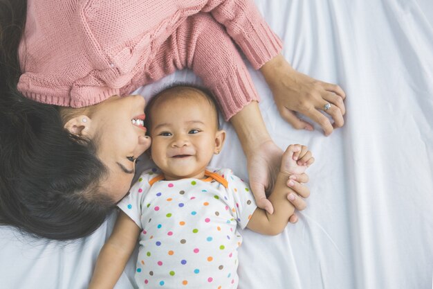 Jonge moeder die met haar baby op bed legt