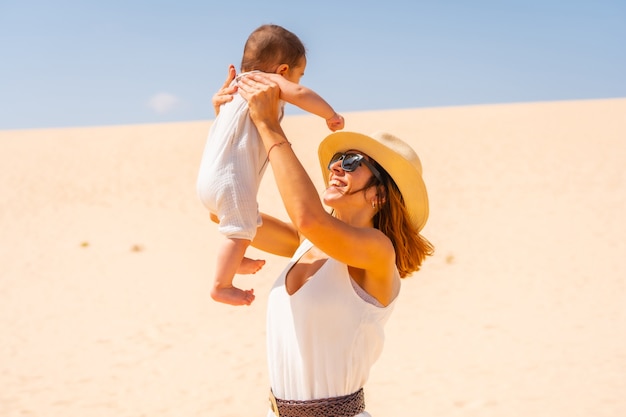 Jonge moeder die plezier heeft met haar zoon op vakantie in de duinen van het natuurpark Corralejo, Fuerteventura, Canarische Eilanden. Spanje