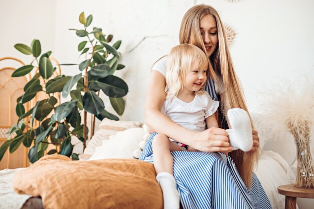 Foto jonge moeder die sokken aan haar kind zet