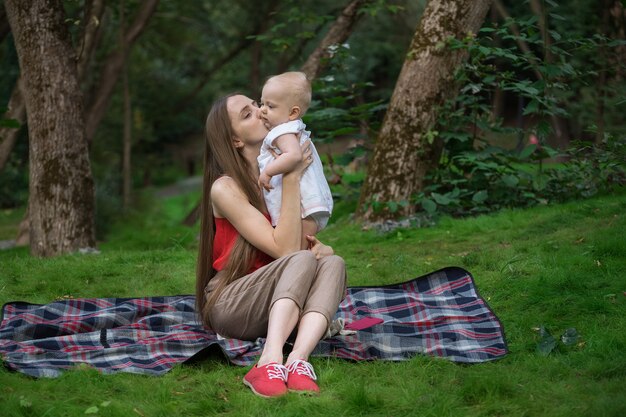 Jonge moeder die teder haar baby op aardachtergrond koestert. Saamhorigheid ontspanning concept met kind.