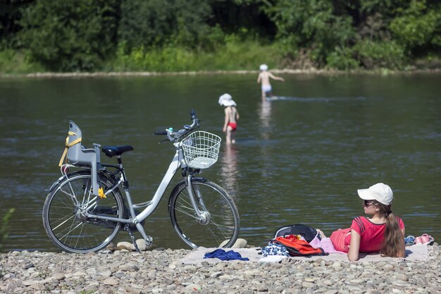 Jonge moeder die voor haar kinderen aan de oever van de rivier zorgt