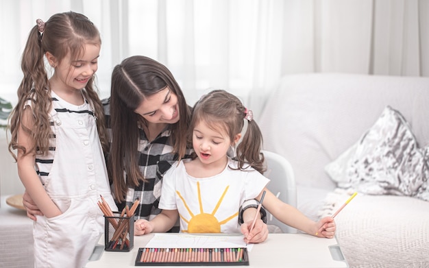 Jonge moeder doet huiswerk met kleine dochters. thuisonderwijs en onderwijsconcept.