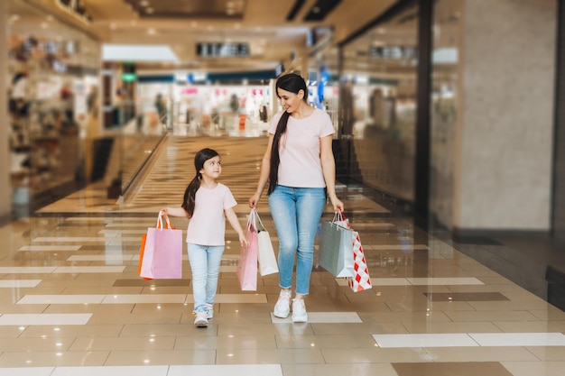Jonge moeder en dochter houden boodschappentassen winkelen in het winkelcentrum Familie winkelen