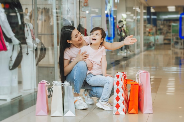 Jonge moeder en dochter houden boodschappentassen winkelen in het winkelcentrum Familie winkelen