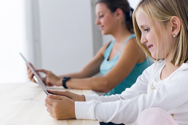 Jonge moeder en dochter spelen thuis met een digitale tablet.