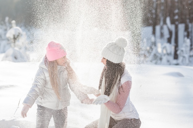 Jonge moeder en haar dochter die pret in de sneeuw hebben