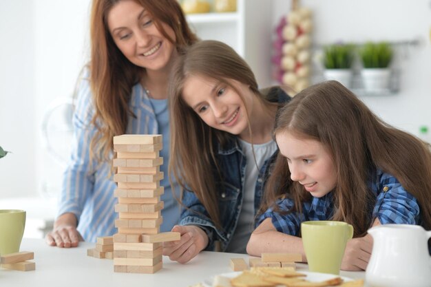 Jonge moeder en haar dochters spelen met houten blokken