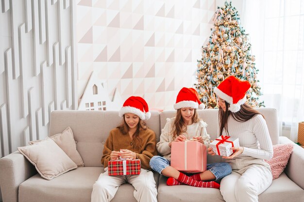 Jonge moeder en haar dochtertjes met cadeautjes onder de kerstboom