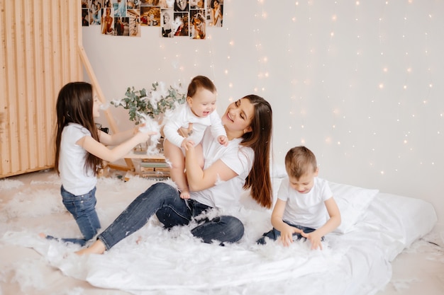 jonge moeder en haar drie kinderen in jeans en t-shirts spelen met plezier zittend op de vloer