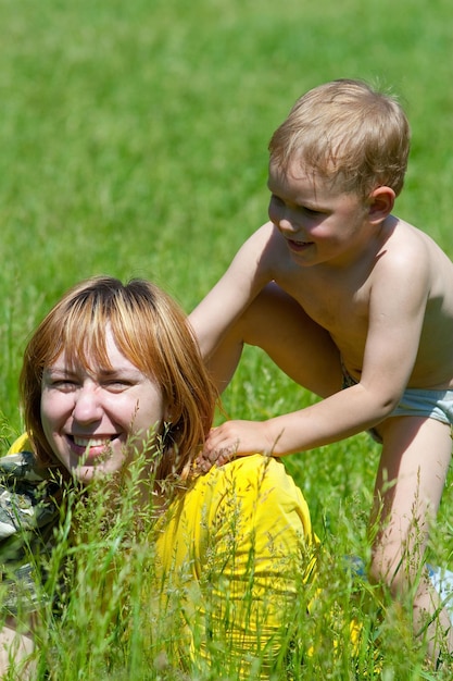 Jonge moeder en haar eenjarige dochter rusten in het park op het gras Familie die samen plezier heeft