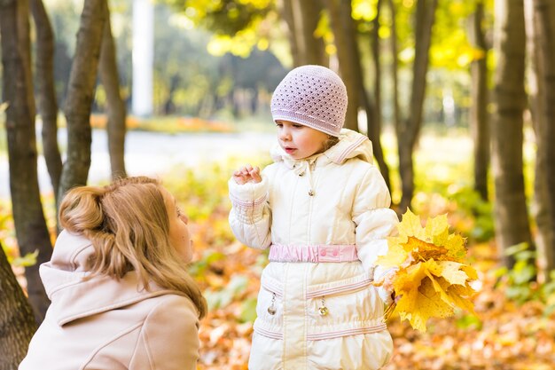 Jonge moeder en haar peutermeisje hebben plezier in de herfst