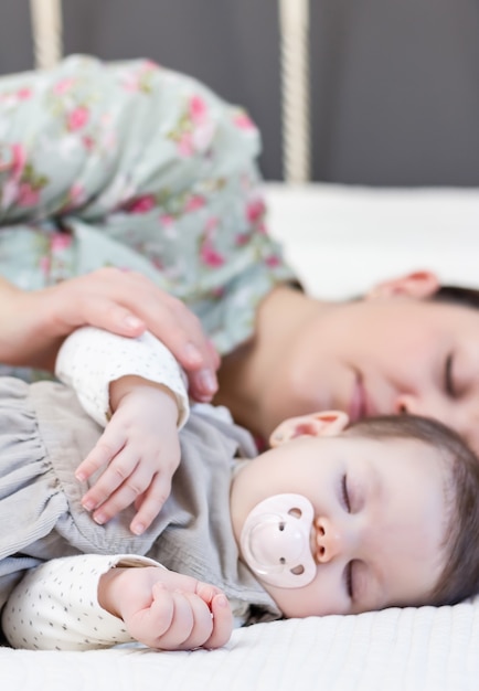 Jonge moeder en haar schattige babymeisje slapen samen in bed