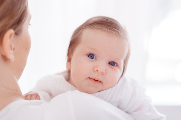 Jonge moeder en pasgeboren baby in witte slaapkamer