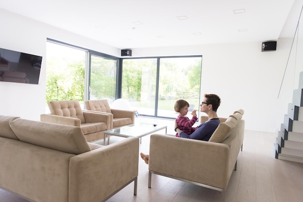 jonge moeder en schattig klein meisje genieten van hun vrije tijd knuffelend op de bank in hun luxe huisvilla