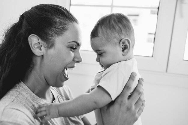 Jonge moeder heeft een teder moment met haar baby thuis Zachte focus op moederoog Zwart-witbewerking