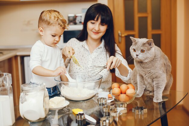 jonge moeder in een wit overhemd bereiden van voedsel thuis in de keuken met haar zoontje